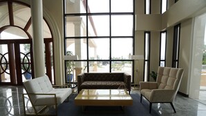 A spacious lobby with a large window, a sofa, two armchairs, and a coffee table. - Hotel Oazis Butuan (Butuan)