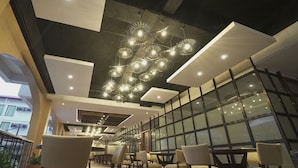 A modern interior with a long dining area, multiple tables and chairs, and a unique ceiling light fixture. - Hotel Oazis Butuan (Butuan)
