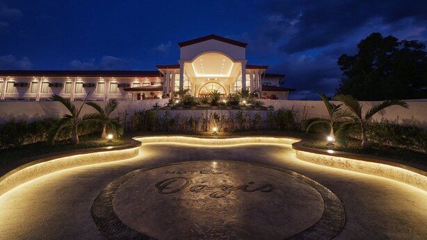 A modern hotel with a central courtyard, a well-lit entrance, and a large circular emblem on the ground. - Hotel Oazis Butuan (Butuan)
