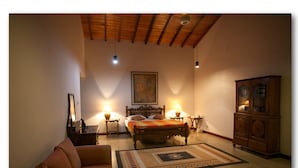 A bedroom with a bed, a wooden cabinet, a sofa, and two bedside tables with lamps.
