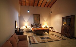 A bedroom with a bed, a wooden cabinet, a sofa, and two bedside tables with lamps.