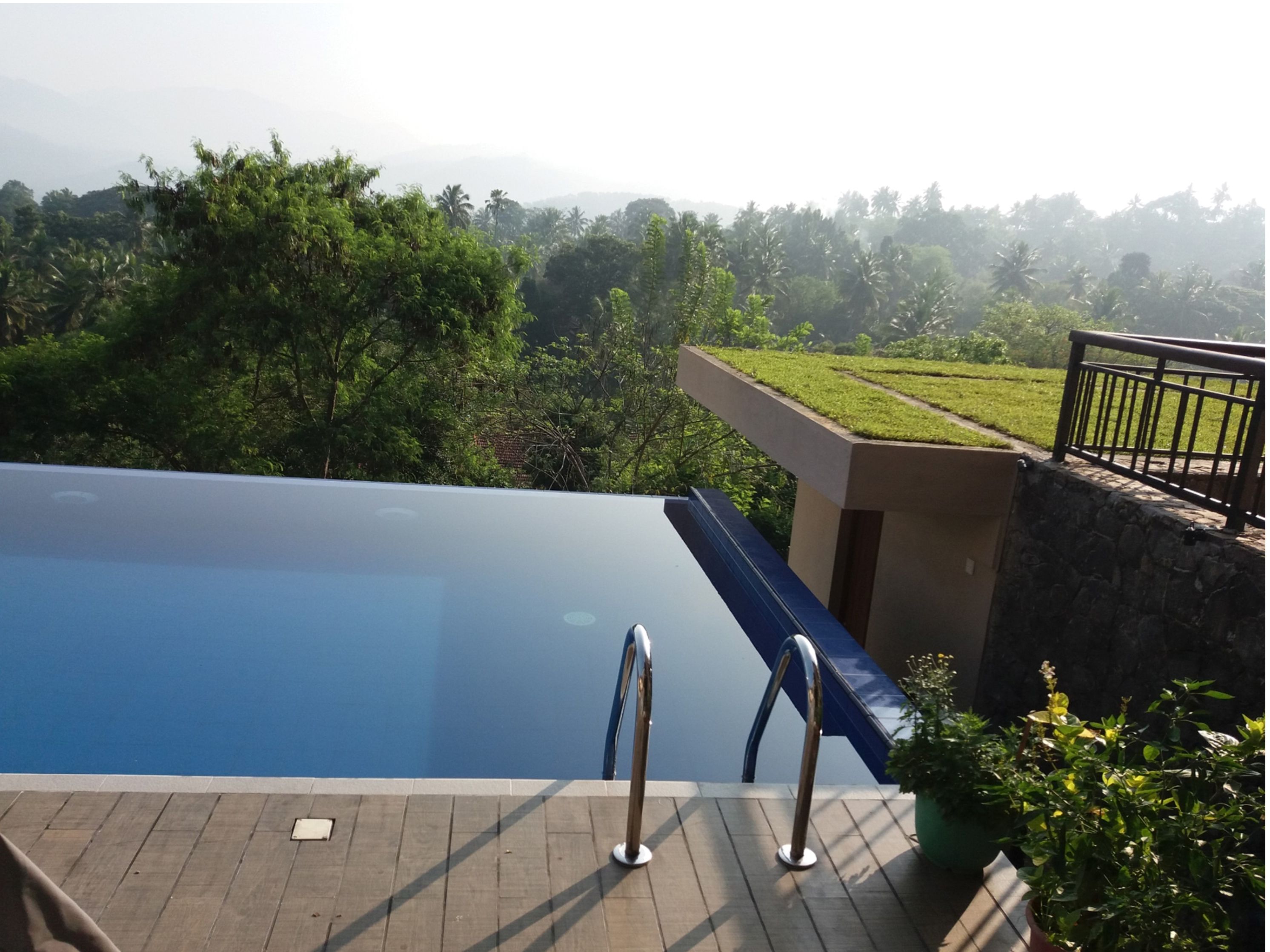 A swimming pool with a view of a lush landscape and a stone wall.