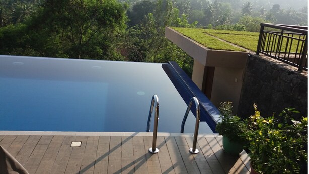 A swimming pool with a view of a lush landscape and a stone wall. - Tranquility in a golf and country resort- Luxury villa with live-in cook & staff (Rajawella)