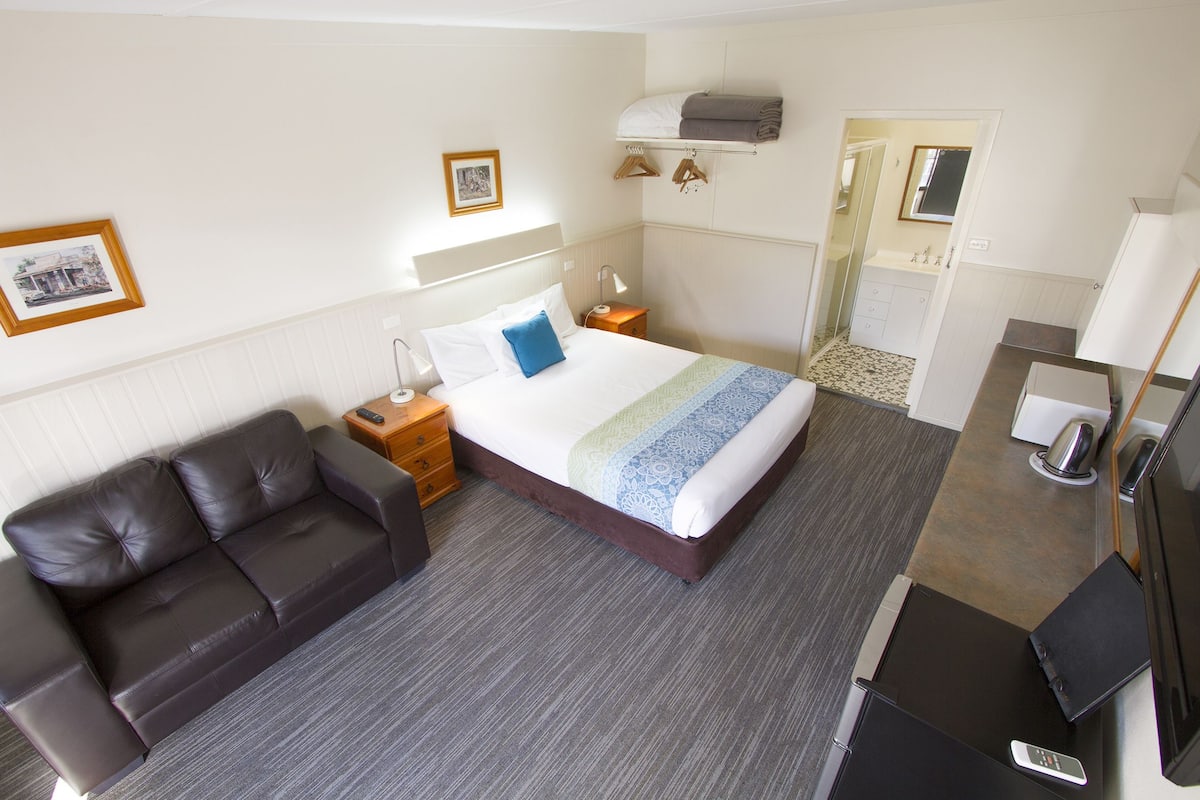 Quarto de hotel com cama, sofá, escrivaninha e banheiro.
