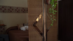 A bedroom with a bed, a decorative wall, and a plant.