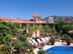 Een resort met een zwembad, ligbedden en een berg op de achtergrond.