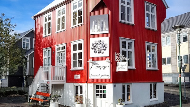 En rød bygning med hvide detaljer, en trappe og plantekasser.