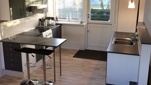 Eine moderne Küche mit schwarzem Arbeitsplatz, Edelstahlgeräten und einem Fenster mit Jalousien.