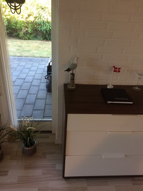 Un interior moderno con un mostrador de recepción de madera, una planta en maceta, una pequeña bandera y un libro titulado 'Gastebog'.
