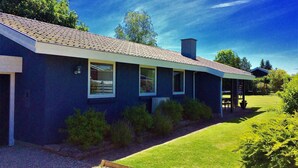 Ein modernes Haus mit dunkelblauer Fassade, einem geneigten Dach und einer überdachten Veranda.