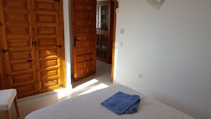 Ein Zimmer mit einem Bett, einem weißen Stuhl und Holztüren.