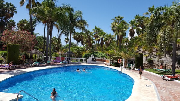 A pool area with a clear blue pool, lounge chairs, and palm trees. - Penthouse Villa with 360 degree panoramic sea, mountain views (Nerja)