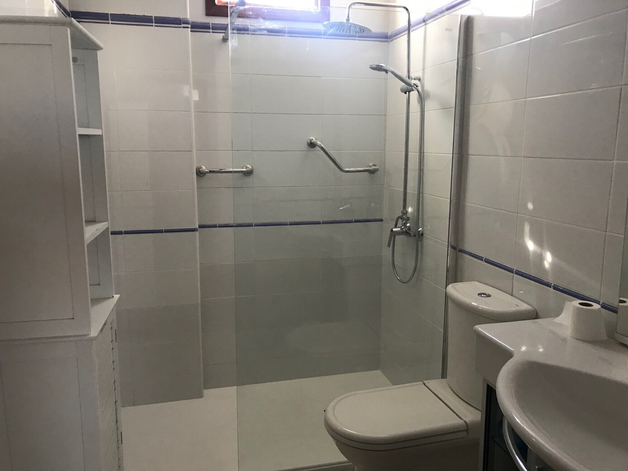 A small, tiled bathroom with a shower, toilet, and sink.