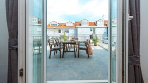 A balcony with a table and chairs, a potted plant, and a view of neighboring houses. - 2 bedroom, 2 bathroom Apartment in Lapad with a large terrace and parking (Dubrovnik)