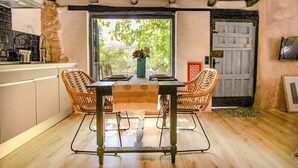 A dining area with a table, chairs, and a view through a window. - HOHLE Cave Suite (Cave Hotel Lomas de Ruvira) (Jorquera)