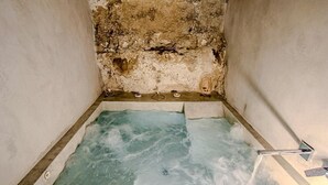 A small, rectangular hot tub with a rough, textured wall behind it. - HOHLE Cave Suite (Cave Hotel Lomas de Ruvira) (Jorquera)