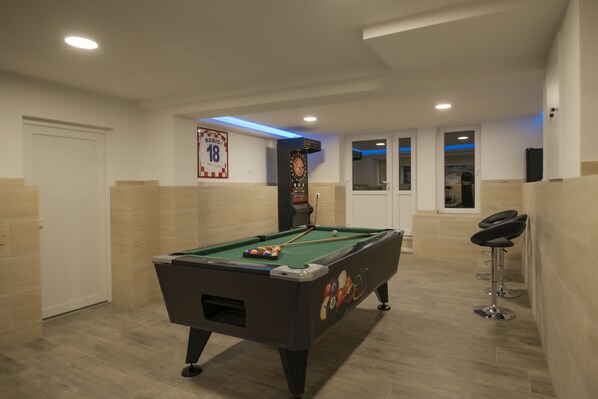 A pool table in a room with beige walls and a door.