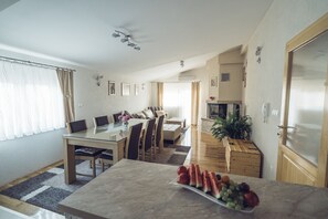 A modern living room with a dining area, a kitchen, and a large window with curtains. - COZY HOUSE HEATED POOL, NEAR BEACH IN SPLIT COUNTY (Imotski)