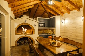A cozy kitchen with a fireplace, wooden beams, and a dining area with a chessboard.
