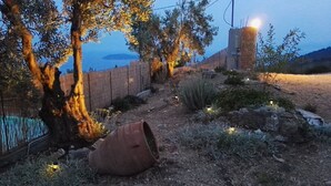 A rustic outdoor setting with a dirt path, a wooden fence, and a large tree with a trunk wrapped in rope. - ANGIO LUXURIUS VILLAS IN SKIATHOS (SKIATHOS)