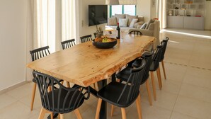 A dining area with a wooden table, black chairs, a bowl of fruit, and a wine bottle. - ANGIO LUXURIUS VILLAS IN SKIATHOS (SKIATHOS)