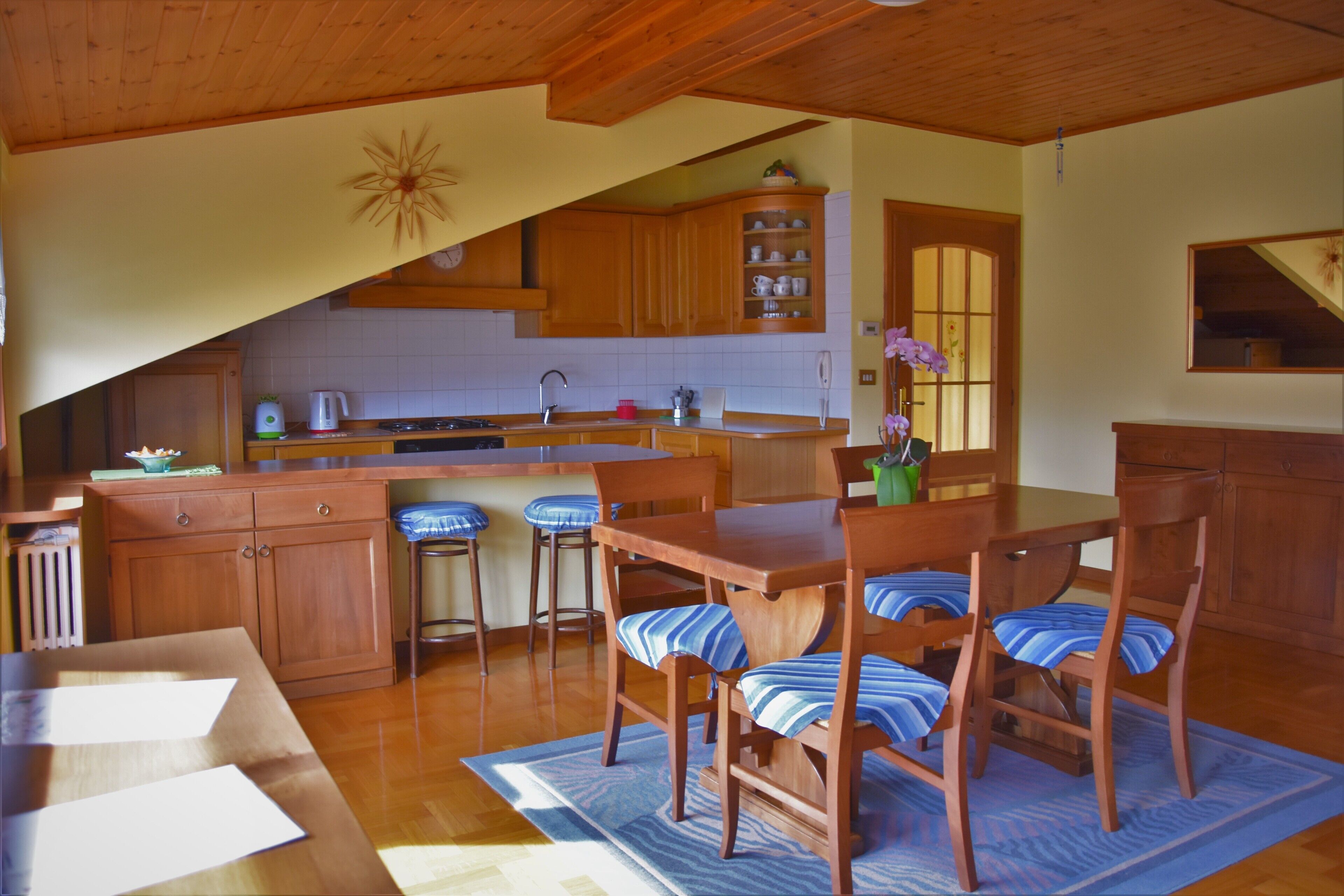 A kitchen with wooden cabinets, a dining table with chairs, and a kitchen island.