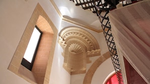Una escalera con barandilla de hierro forjado, una ventana y un arco de piedra decorativo.