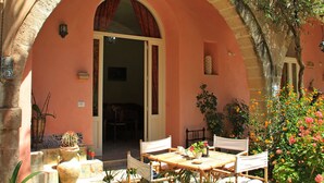 Un patio al aire libre con una mesa, sillas, una planta en maceta y un acceso a un espacio interior.