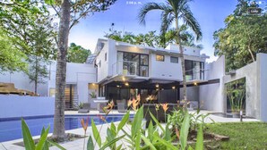 A modern two-story house with a pool, surrounded by tropical plants and palm trees. - MODERN AND MAGICAL VILLA WALKING DISTANCE FROM THE BEACH!  (Guanacaste)