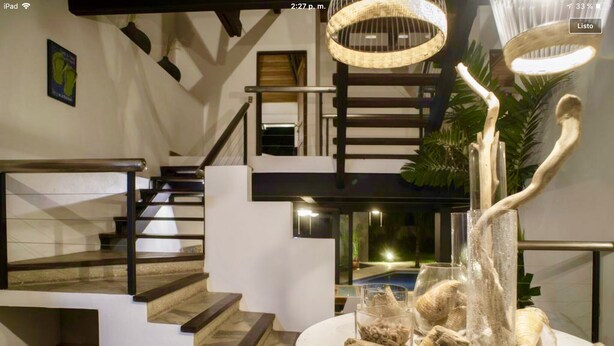 A modern interior with a staircase, a dining area with a centerpiece, and a view of a pool. - MODERN AND MAGICAL VILLA WALKING DISTANCE FROM THE BEACH!  (Guanacaste)