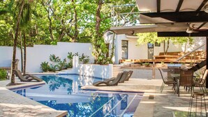 A swimming pool with lounge chairs, a covered outdoor seating area, and a staircase leading to a second level. - MODERN AND MAGICAL VILLA WALKING DISTANCE FROM THE BEACH!  (Guanacaste)