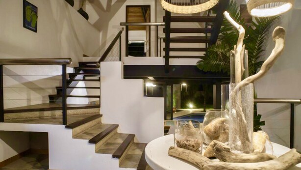Een modern interieur met een trap, een eethoek met middelpunt en uitzicht op een zwembad.