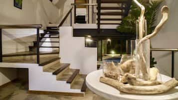 Un intérieur moderne avec un escalier, un coin repas agrémenté d’un élément décoratif central et une vue sur une piscine.