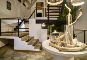 A modern interior with a staircase, a dining area with a centerpiece, and a view of a pool. - MODERN AND MAGICAL VILLA WALKING DISTANCE FROM THE BEACH!  (Guanacaste)