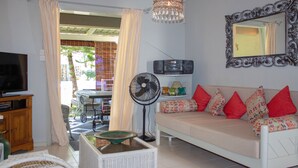 A living room with a sofa, television, fan, and decorative items.