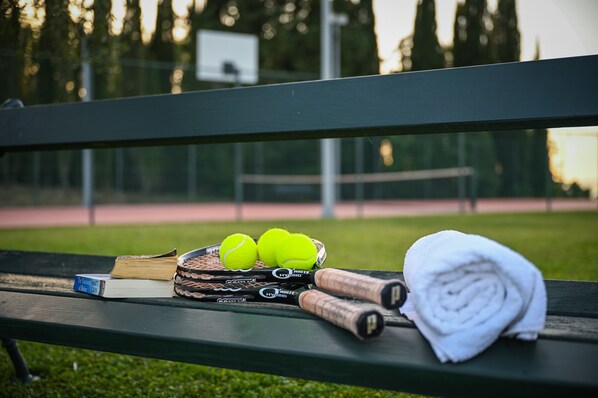 A bench with a book, tennis balls, and a towel.