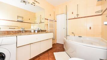 A modern bathroom with a large bathtub, a double sink vanity, and a built-in washing machine.