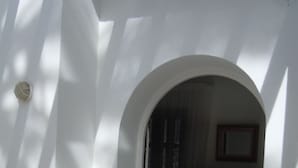 Ein Zimmer mit weißer Wand, einem rundbogigen Durchgang, einer kleinen Stufe zum Badezimmer und einem Schrank mit Schubladen.