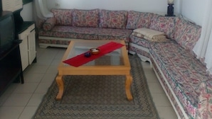 Ein Wohnzimmer mit einer Couch, einem Couchtisch, einem Fernseher und Kunstwerken an der Wand.