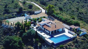Vue aérienne d’une villa moderne dotée d’une piscine, de plusieurs bâtiments et d’un jardin aménagé.