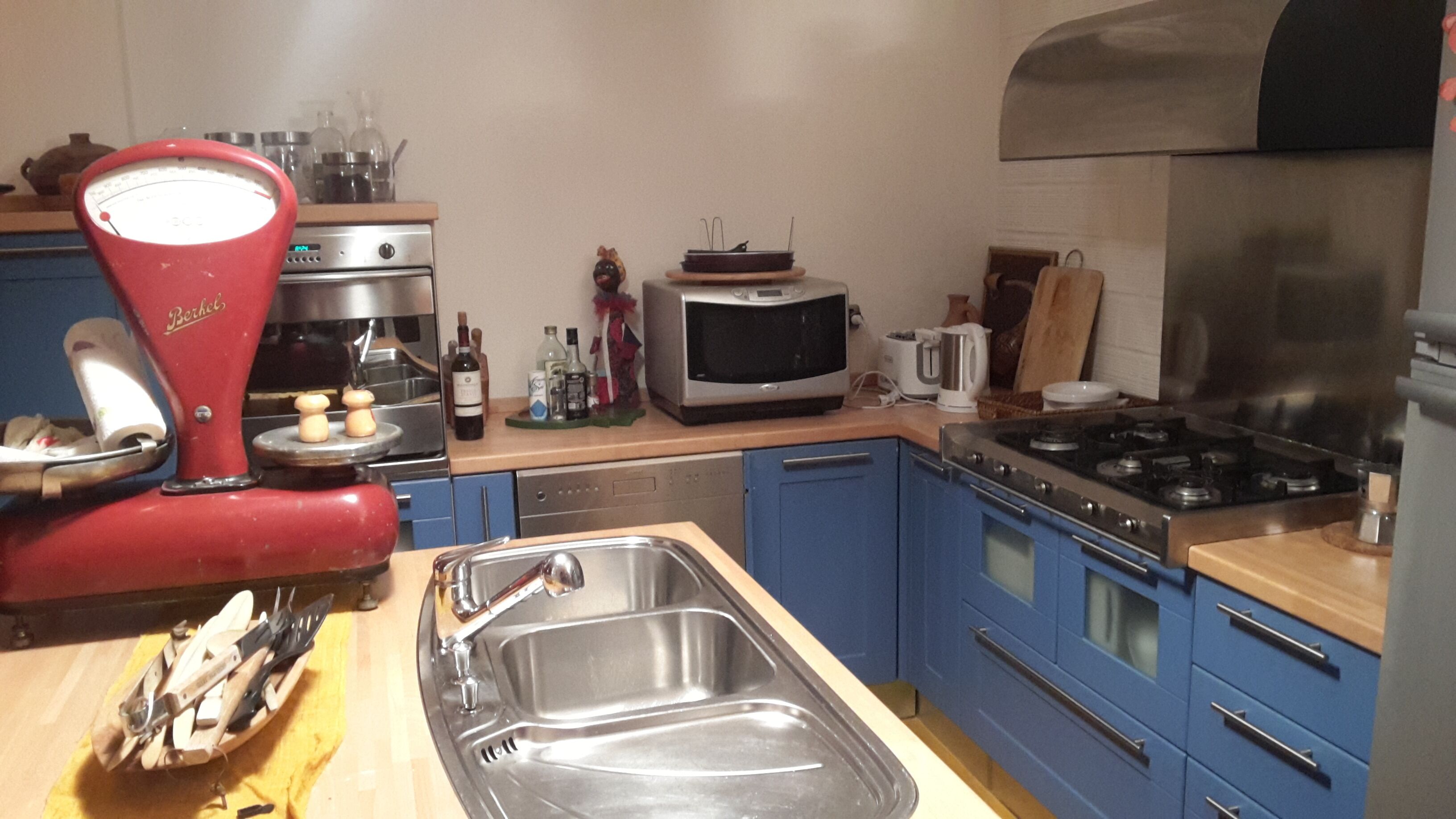 A kitchen with a red coffee maker, a microwave, a stove, and blue cabinets.