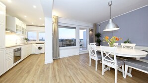 A modern kitchen with a built-in oven, a washing machine, and a dining area with a round table and chairs. - PORAT Apartment-Breathtaking sunset view in Zadar, Croatia (Zadar)