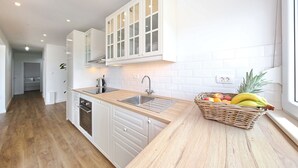 A modern kitchen with white cabinetry, a wooden countertop, and a fruit basket. - PORAT Apartment-Breathtaking sunset view in Zadar, Croatia (Zadar)