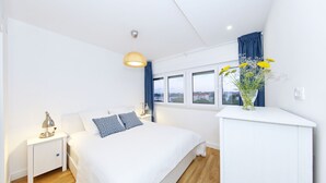 A modern bedroom with a large bed, bedside tables, a desk, and a window with a view. - PORAT Apartment-Breathtaking sunset view in Zadar, Croatia (Zadar)