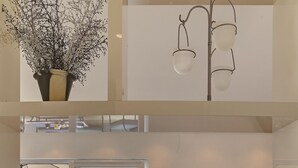 A modern interior with a balcony, a dining area with a tray of food and drinks, and a view of the sea.
