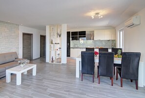 Uma sala de estar moderna com sofá, mesa de centro e área de jantar com cadeiras e mesa.