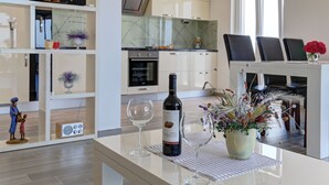 A modern kitchen with white cabinets, a wine bottle, and two glasses on a table.