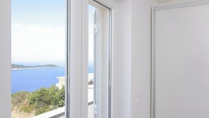 A room with a large sliding glass door leading to a balcony with a sea view.