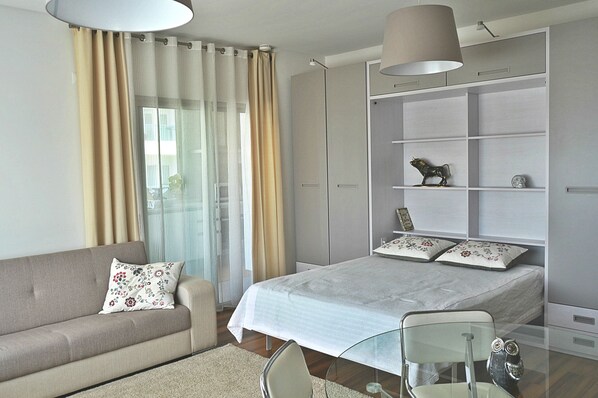 A modern bedroom with a bed, a sofa, a glass table, and a wardrobe.