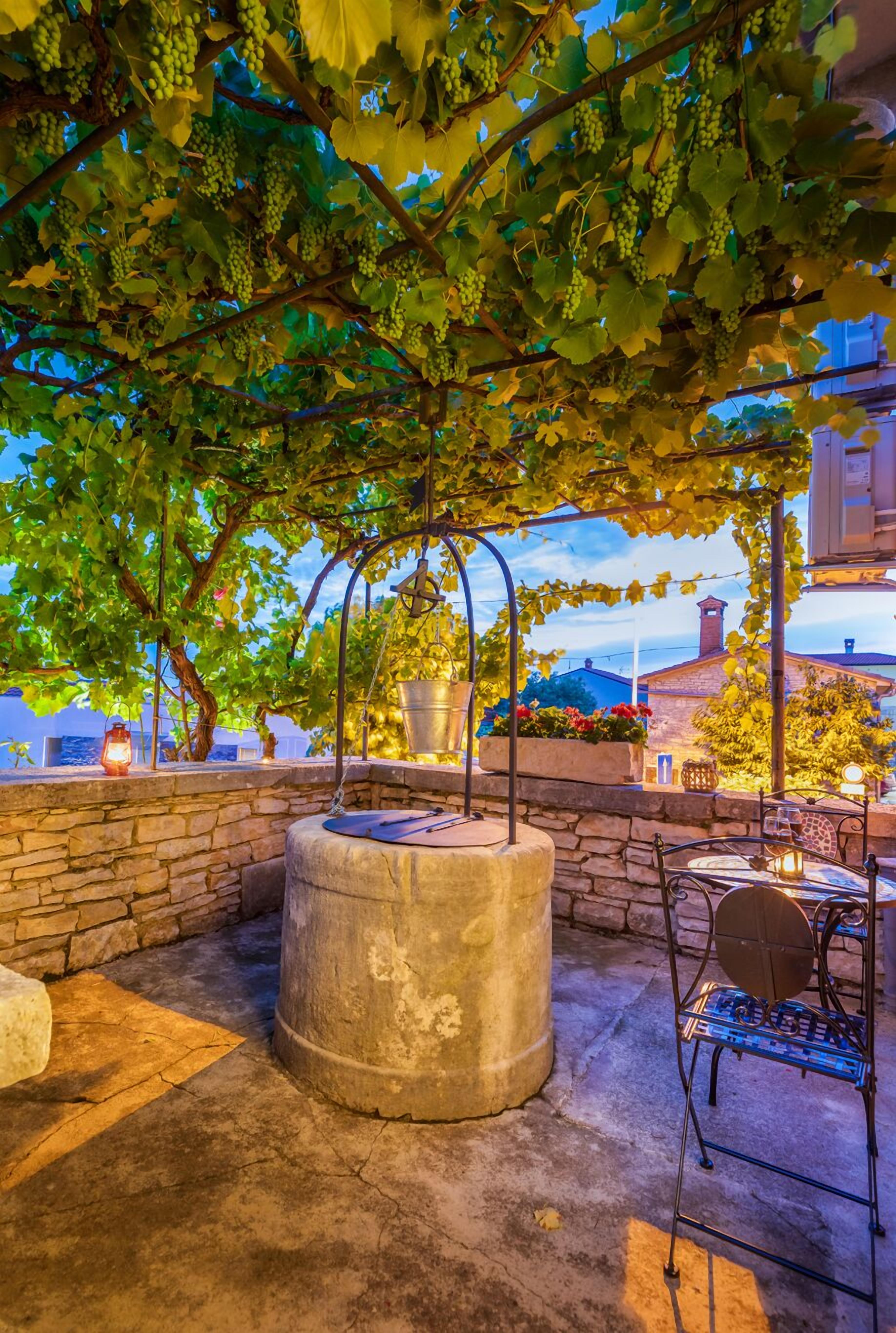 An outdoor seating area with stone walls, a concrete planter, and a metal table.
